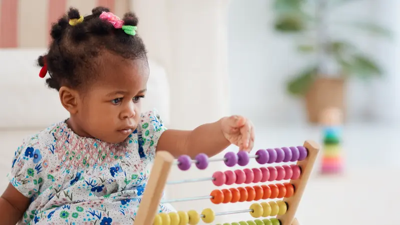 petite fille en train de jouer à un jeu de billes en bois