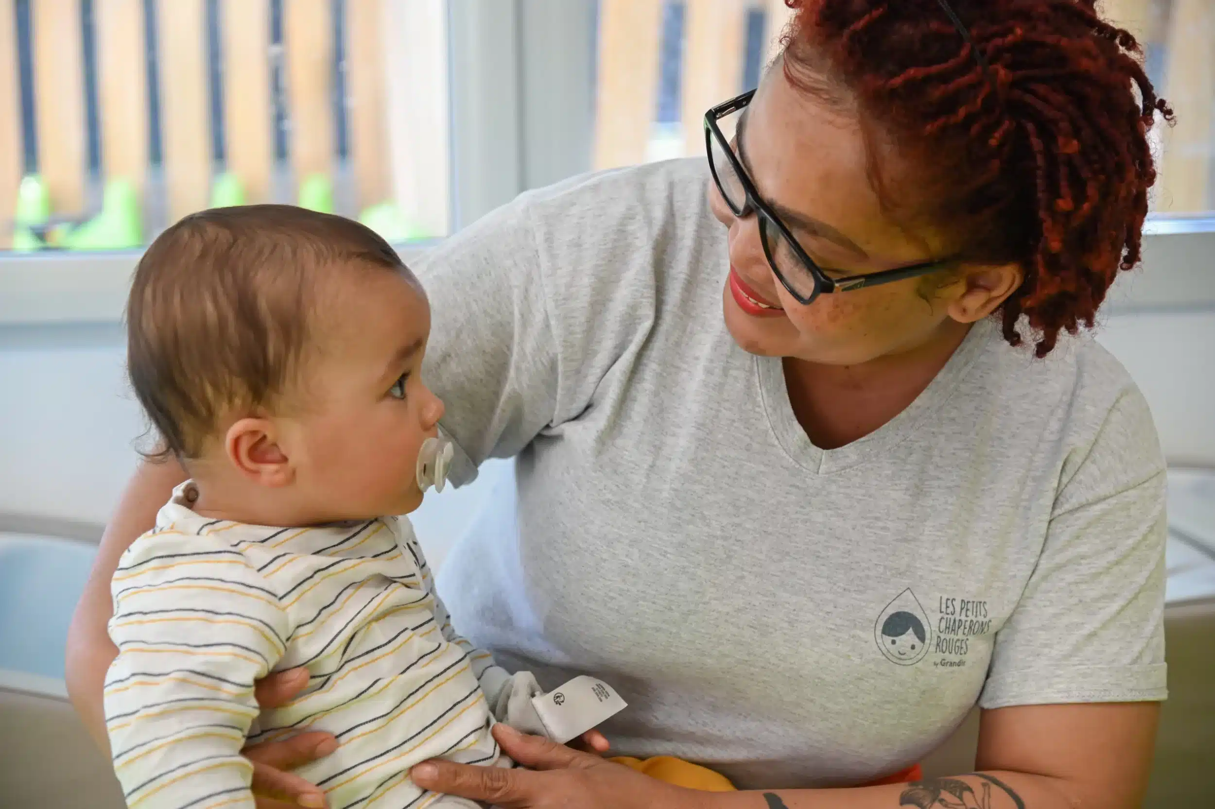 bébé dans les bras d'une professionnelle de crèche souriante